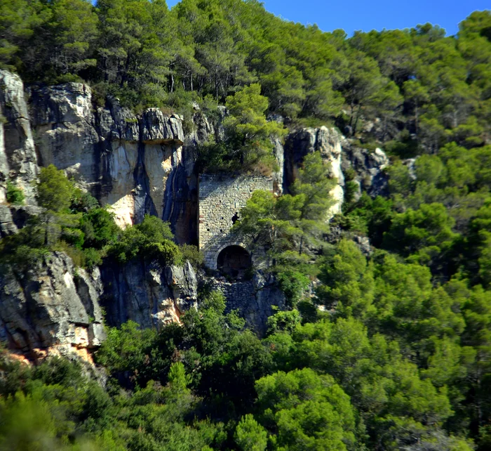 Sant Salvador, «la enderrocada ex-ermita», encastada sota la cinglera a l'altra banda. La fotografia de 2012 en mostra les restes conservades.