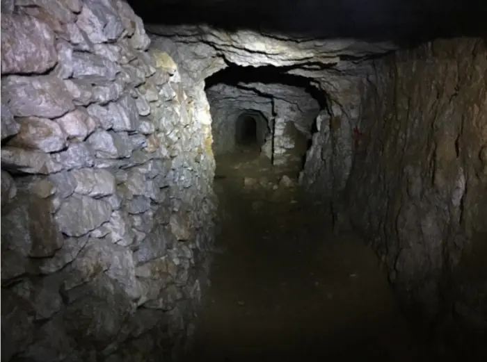 Dins de les Calaveres. A l'esquerra, un mur de pedra seca fet pels miners; al fons, la galeria continua i se n'obre una de transversal. Gomis situa la troballa de l’avenc en l’obertura d’una galeria transversal, sense precisar quina.