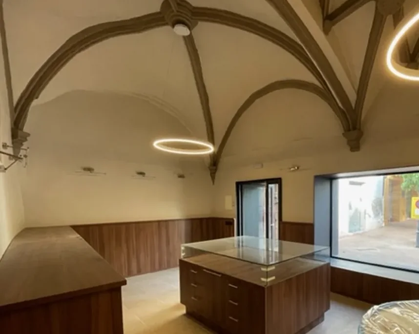 Interior de la capilla del Roser restaurada: la bóveda de nervios vista desde abajo, con el zócalo de madera y una vitrina